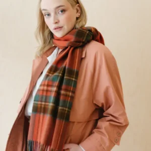 TBCo Lambswool Oversized Scarf in Stewart Royal Antique Tartan styled with peach coat showing plaid pattern and fringe detail
