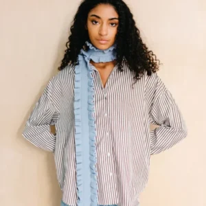 Model wearing TBCo Merino Wool Skinny Scarf in Blue Ruffle with ruffled trim styled over striped shirt and jeans