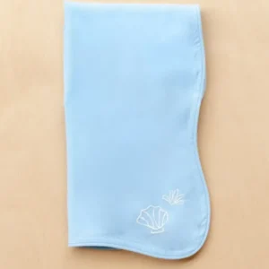 TBCo Cotton & Linen Napkins in light blue with white embroidered seashells and scalloped edges on beige surface
