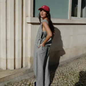 Woman wearing TBCo Denim Barrel Leg Trousers in Herringbone Stripe standing outdoors beside textured stone wall