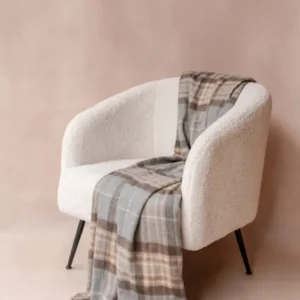 Cashmere Blanket in Mackellar Tartan by TBCo draped over a modern cream armchair with fringed edges.